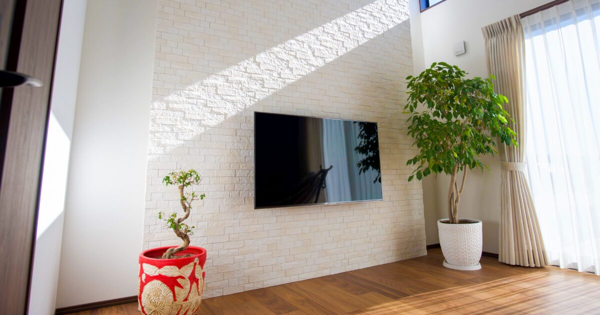 壁掛けテレビと観葉植物がある明るいリビングインテリア