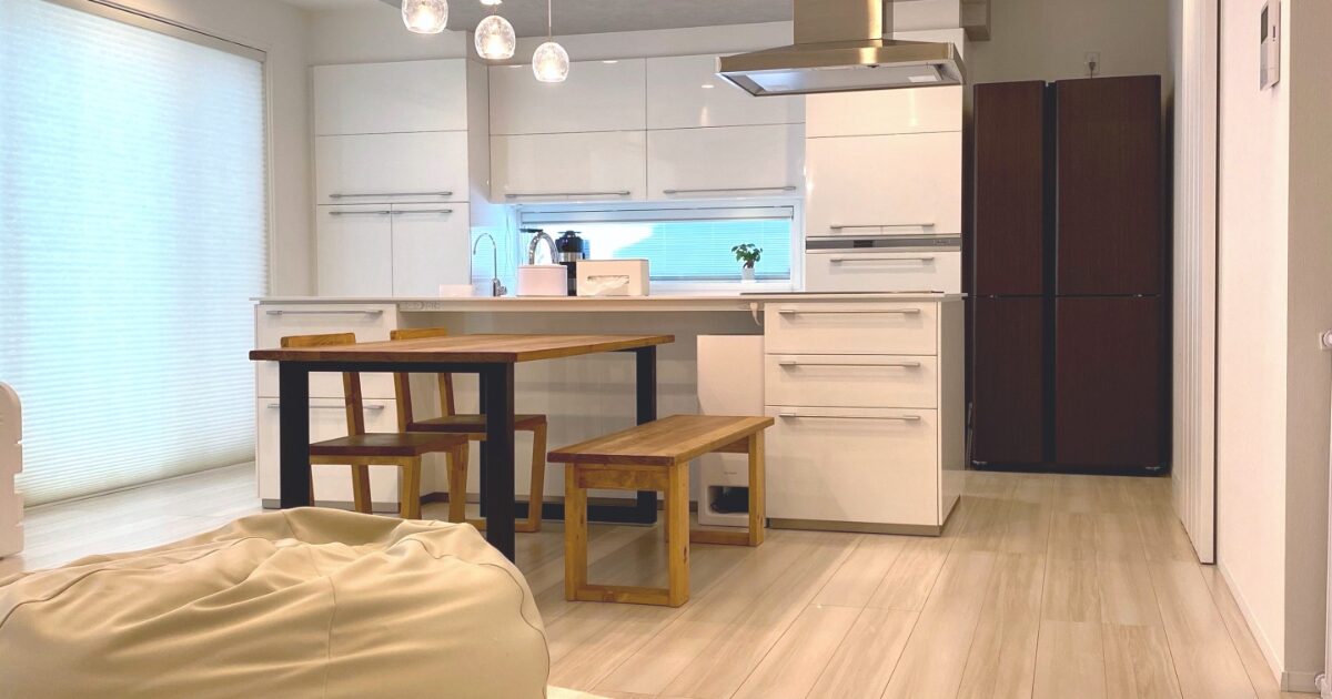 白いアイランドキッチンと木製ダイニングテーブルがあるモダンなLDK