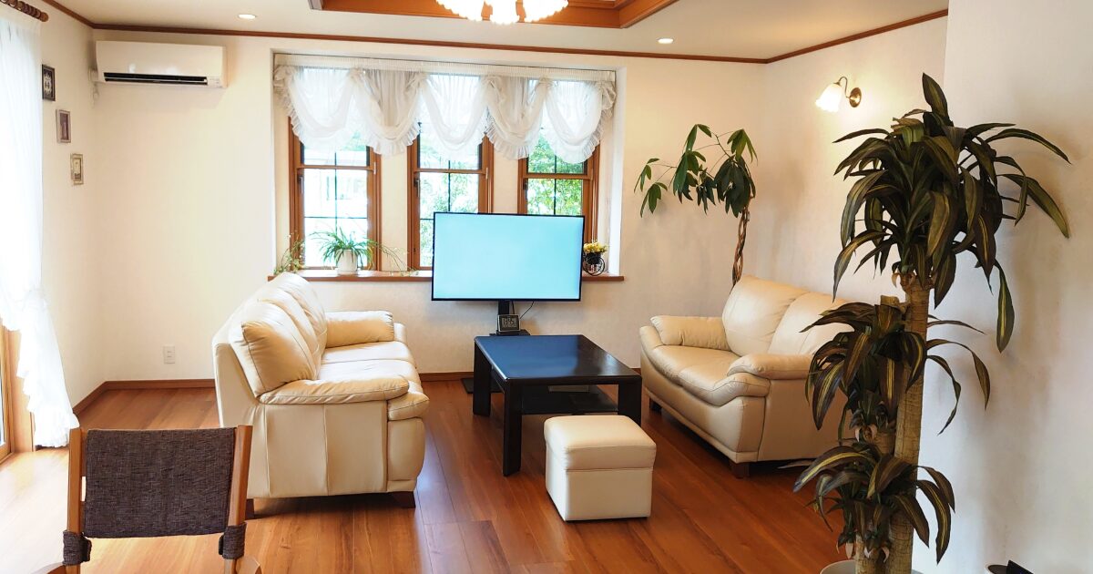 クラシカルなアイボリーソファと観葉植物が調和する上品なリビング